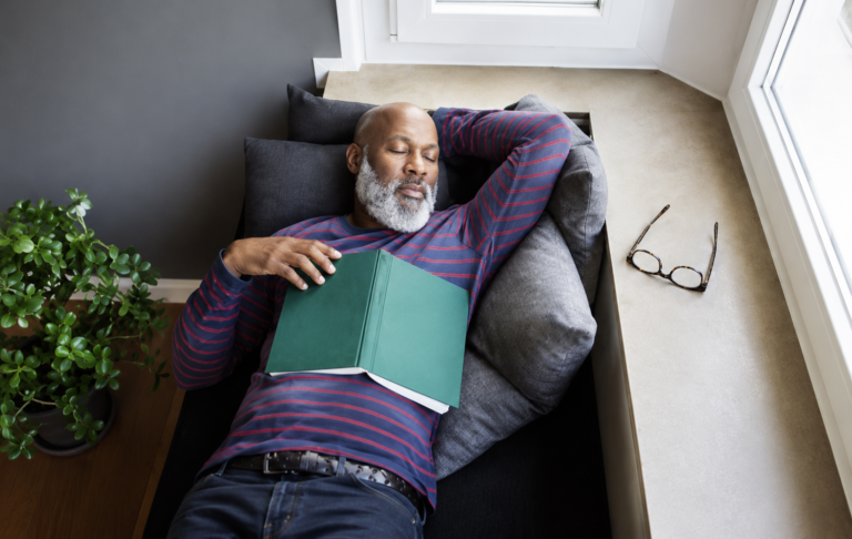 A corporate executive taking a 7-minute power nap at a desk to improve work-life balance and productivity.