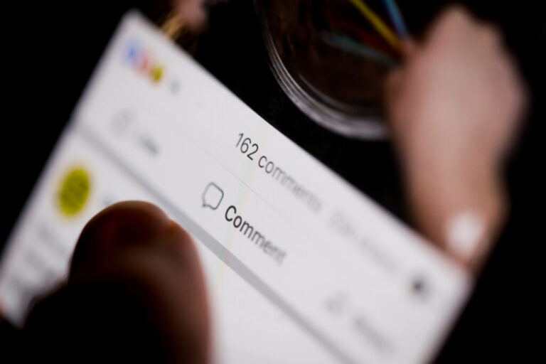 Person holding phone displaying a Facebook post with 162 comments during an online argument